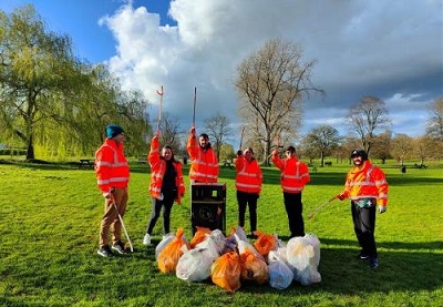 A group of volunteer litter pickers standing around over 10 bags of litter that they have collected from a local park. 