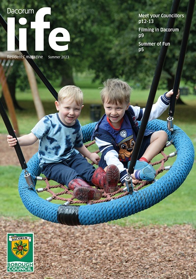 Front cover of the Dacorum Life residents' magazine Summer 2023 with two children playing on a swing