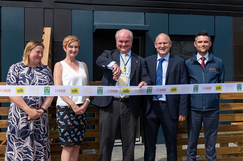 Group shot of 5 people cutting a ribbon in front of a new solohaus