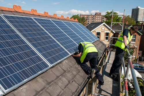 two men installing solar panels on a roof